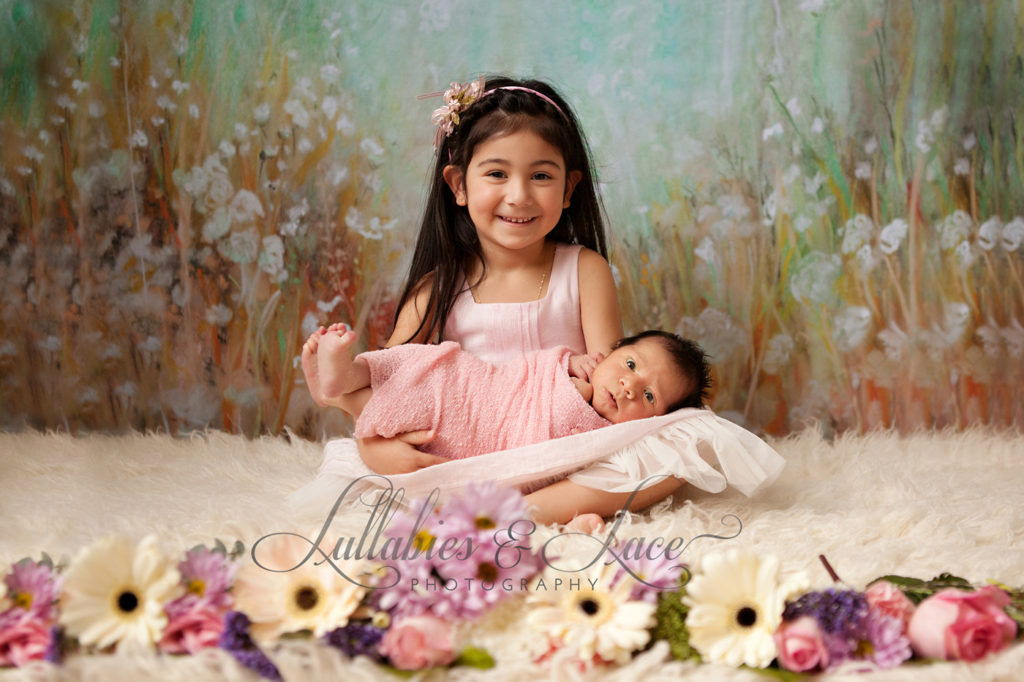 sister with newborn and flowers